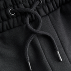 Vista detallada de los pantalones de chándal negros «BVB Essentials» con cordón, un artículo de alta calidad para los aficionados del Borussia Dortmund.