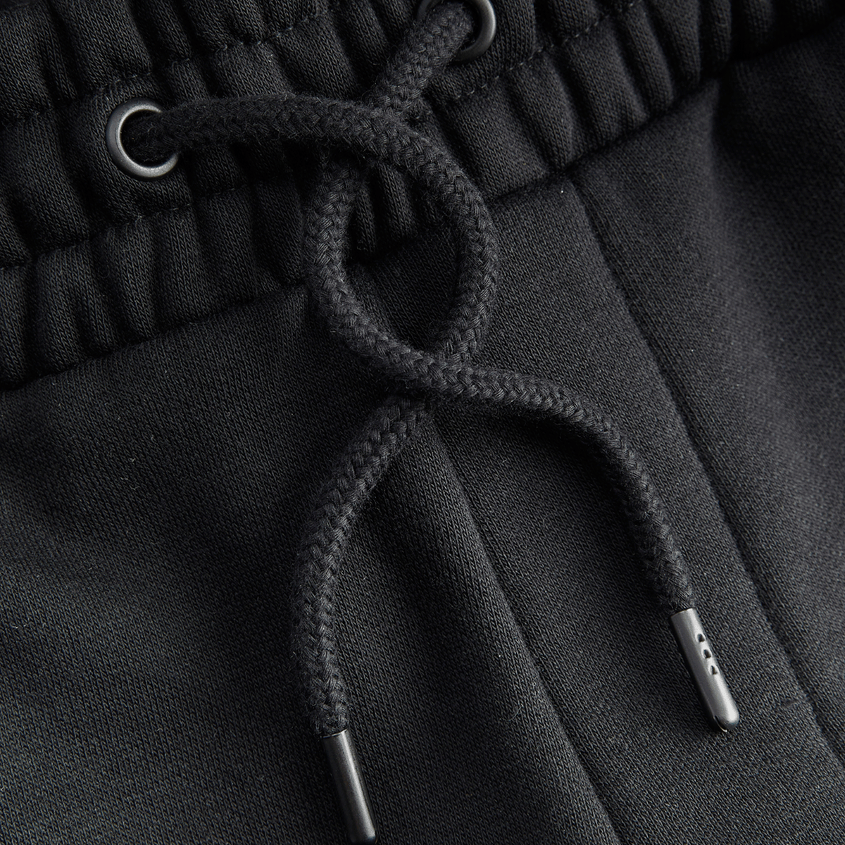 Vista detallada de los pantalones de chándal negros «BVB Essentials» con cordón, un artículo de alta calidad para los aficionados del Borussia Dortmund.
