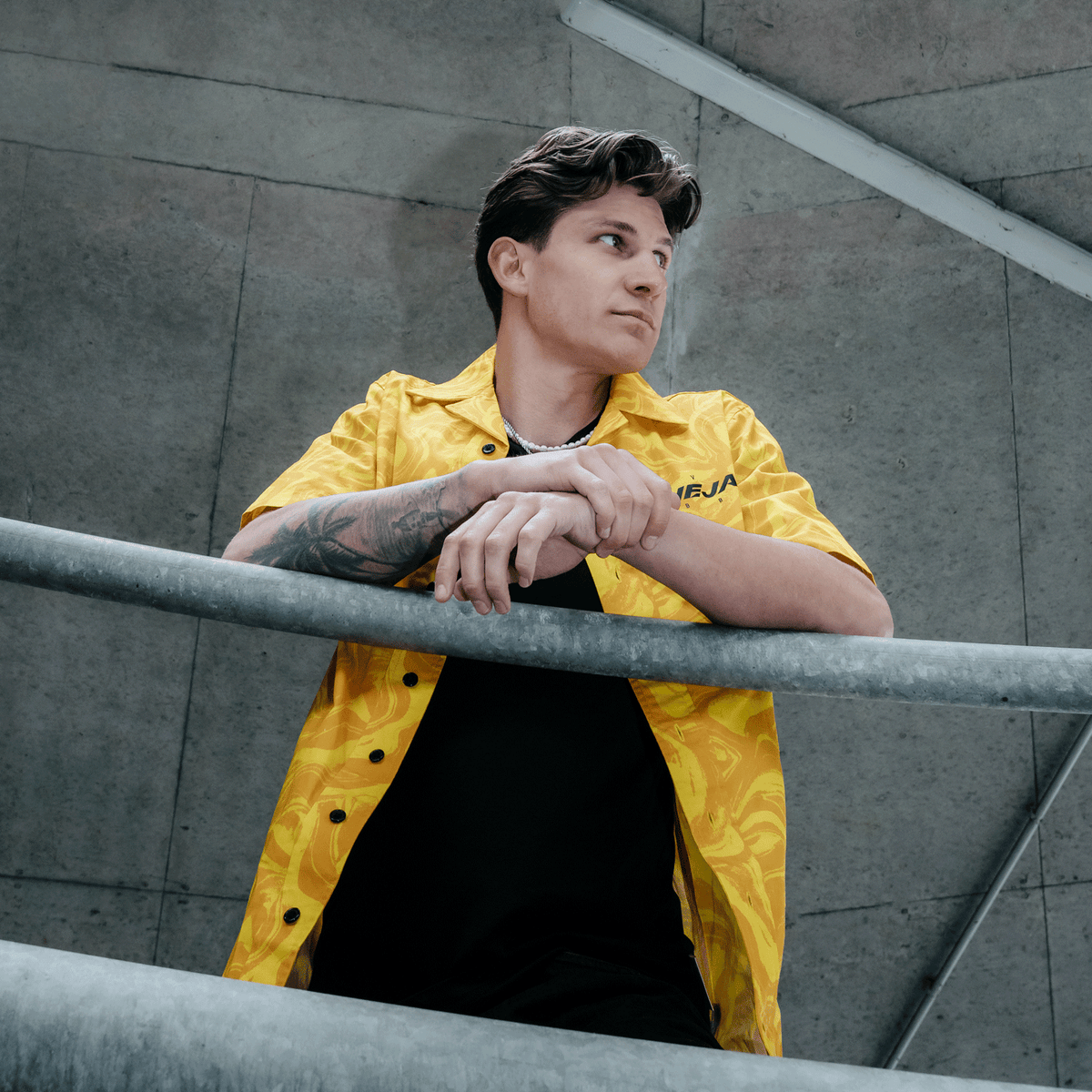 A yellow BVB festival shirt with a black-and-yellow pattern and short sleeves, worn by a man in an urban setting.