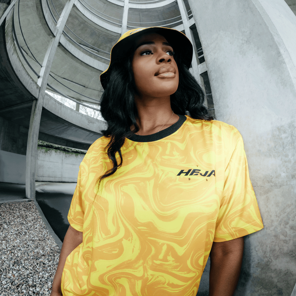 Camiseta del BVB en tonos negro y amarillo con un moderno efecto marmolado y la inscripción «Heja BVB», lucida por una mujer en un entorno urbano.