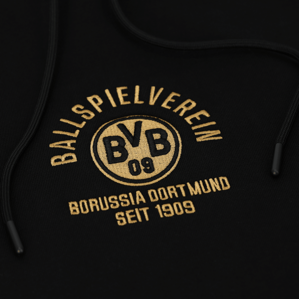 Primo piano di una felpa con cappuccio nera del BVB con la scritta dorata "Ballspielverein Borussia Dortmund seit 1909" e il logo del BVB.