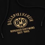 Primo piano di una felpa con cappuccio nera del BVB con la scritta dorata "Ballspielverein Borussia Dortmund seit 1909" e il logo del BVB.