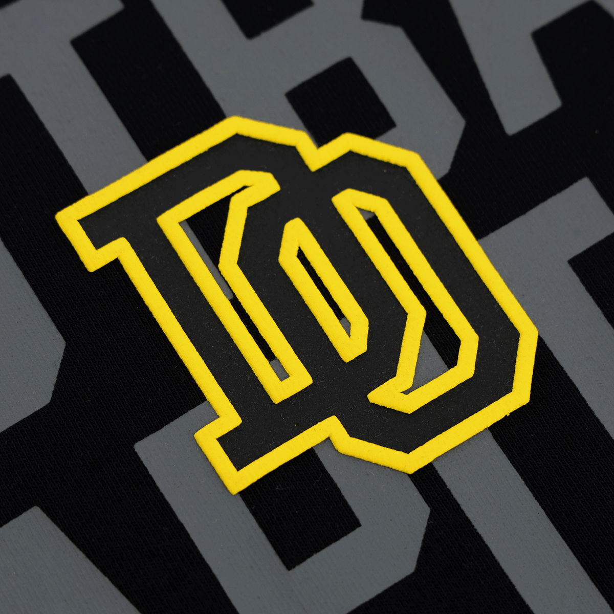 Vue détaillée du t-shirt BVB College noir et jaune, doté d'un logo accrocheur et d'un design moderne, issu de la collection 2025.
