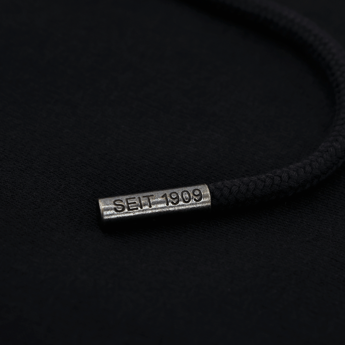 Close-up of a black hood drawstring with a metal tip and embossed "Seit 1909" lettering, designed to match the BVB Matchday II zip jacket.