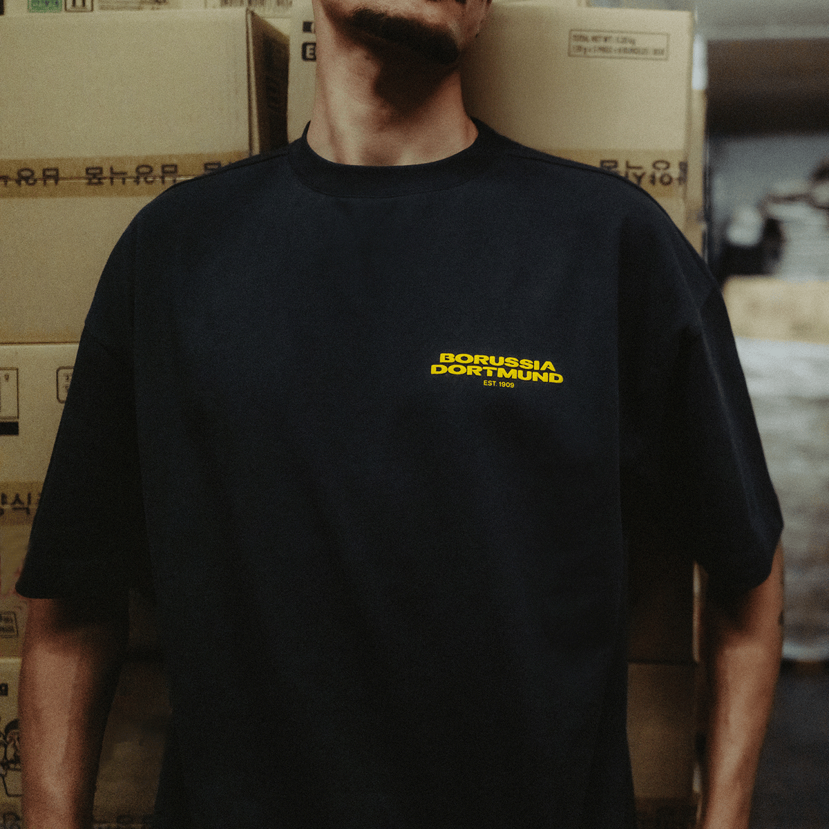 La maglietta BVB Urban in antracite con il logo giallo del Borussia Dortmund e la scritta "EST 1909", ideale per i tifosi della squadra.
