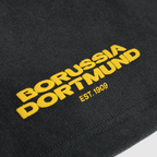 Short BVB Urban anthracite avec logo jaune brodé « Borussia Dortmund EST. 1909 » pour la collection de produits dérivés 2025.
