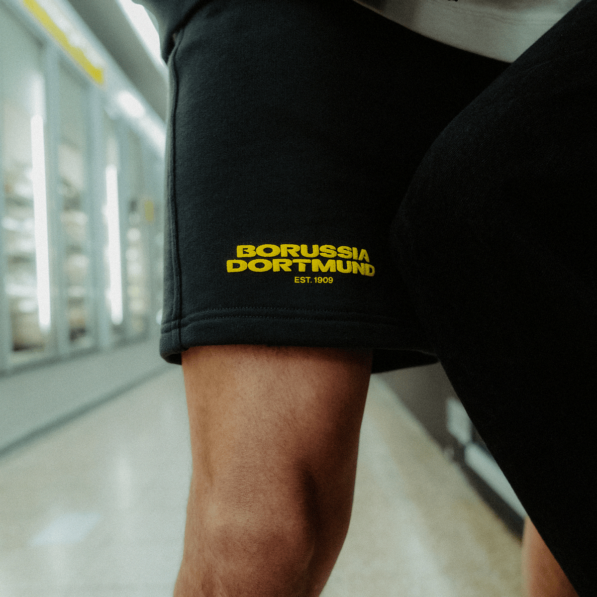 Pantaloncini BVB Urban color antracite con la scritta “Borussia Dortmund” in giallo e la dicitura “EST. 1909” sul lato della gamba.