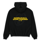 这款黑色多特蒙德（BVB）Urban连帽衫的背面印有黄色字样“Borussia Dortmund”，下方标注“EST. 1909”，背景中还点缀着一个低调的多特蒙德（BVB）队徽。
