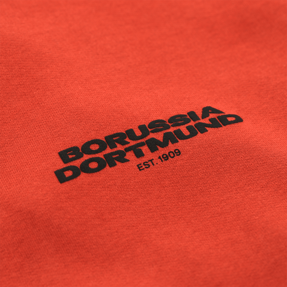 一件橙色BVB Urban连帽衫的特写，上面印有黑色的“Borussia Dortmund”字样和“EST. 1909”标志。