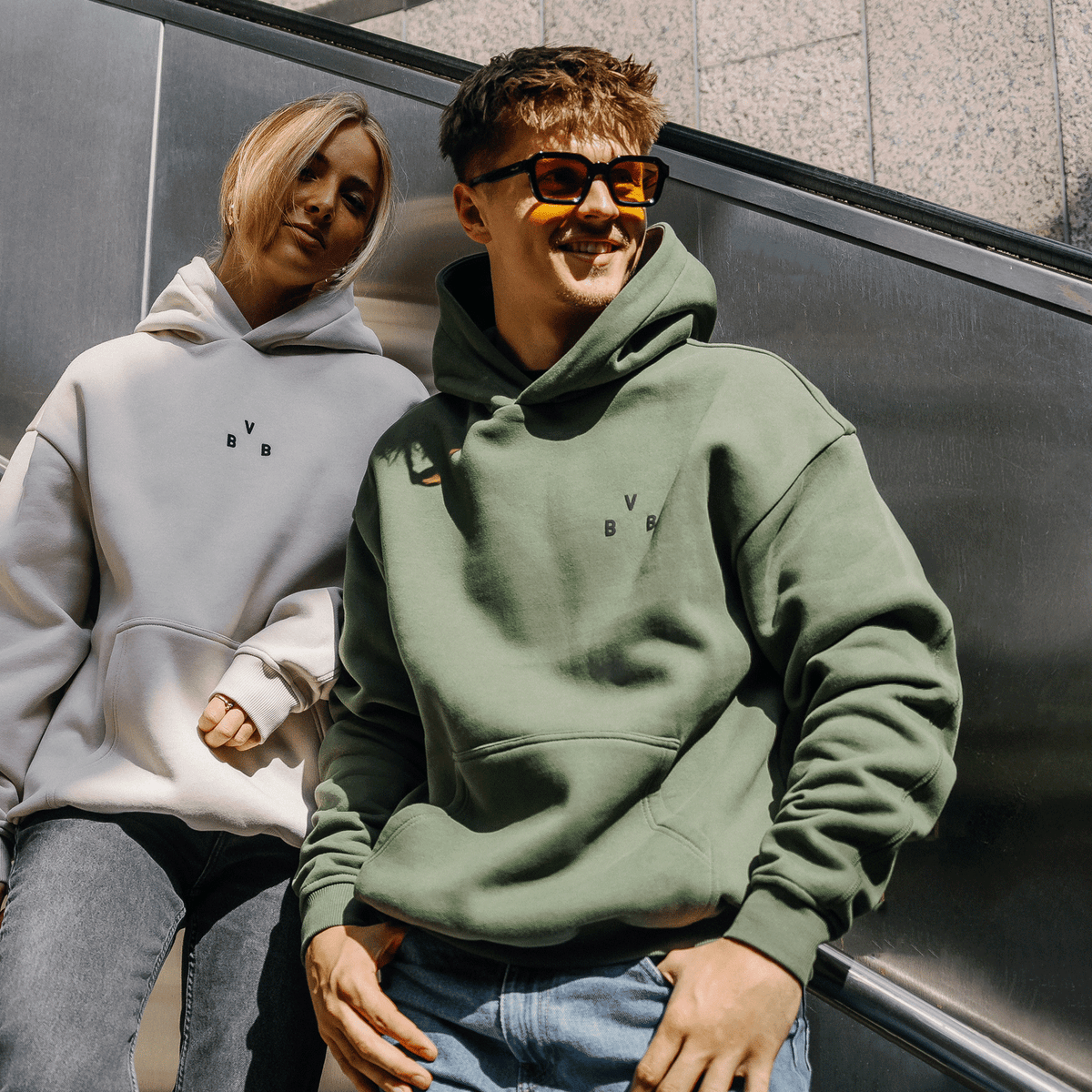 Felpa con cappuccio BVB Urban nei colori verde petrolio e bianco, indossata da due persone, look casual e comodo, ideale per i tifosi del BVB.