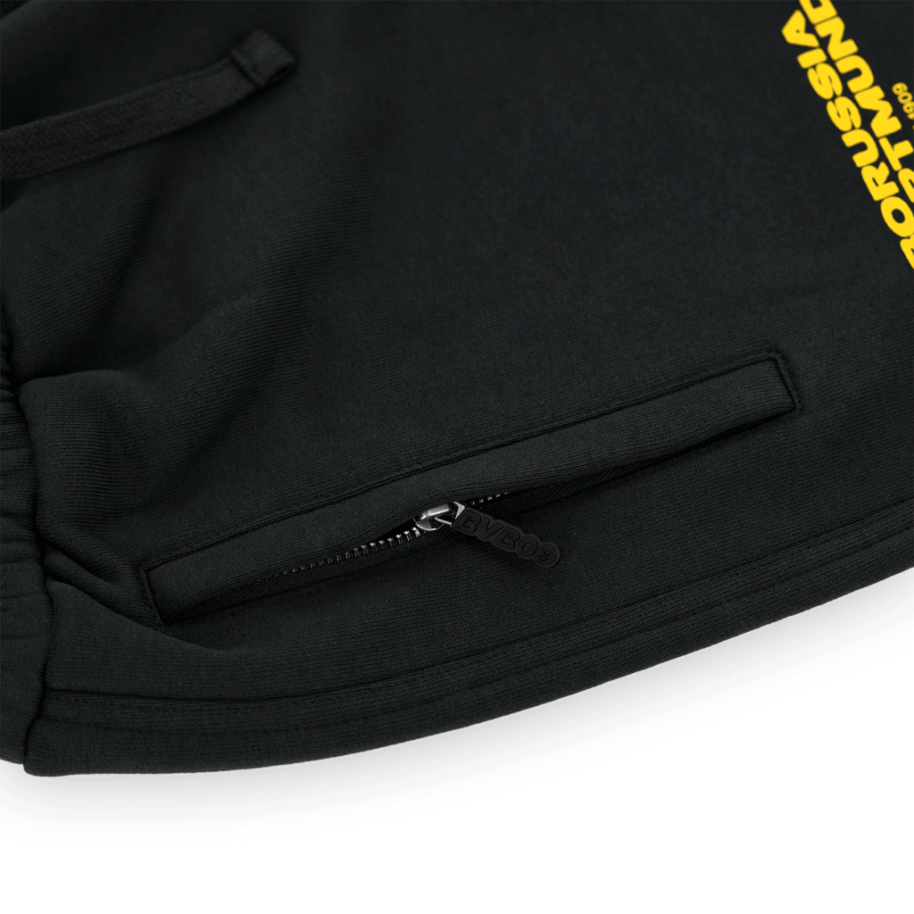 Black BVB urban sweatpants with yellow Borussia Dortmund lettering and practical zippers, ideal for sports and leisure.