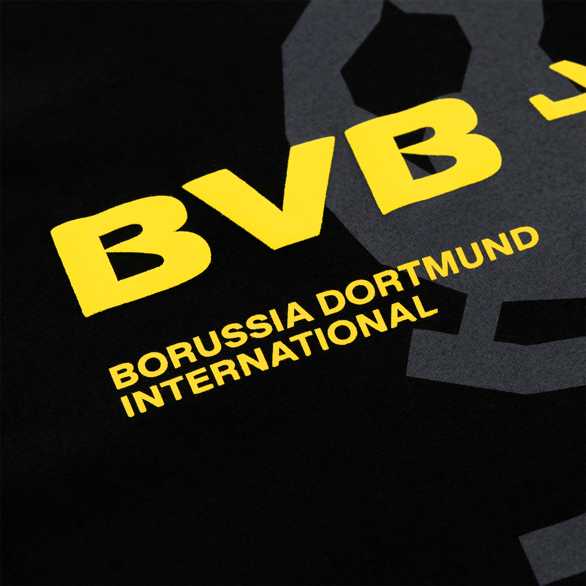 Black-and-yellow BVB T-shirt with yellow "BVB" lettering and "Borussia Dortmund International" text; close-up view of the design on a black background.