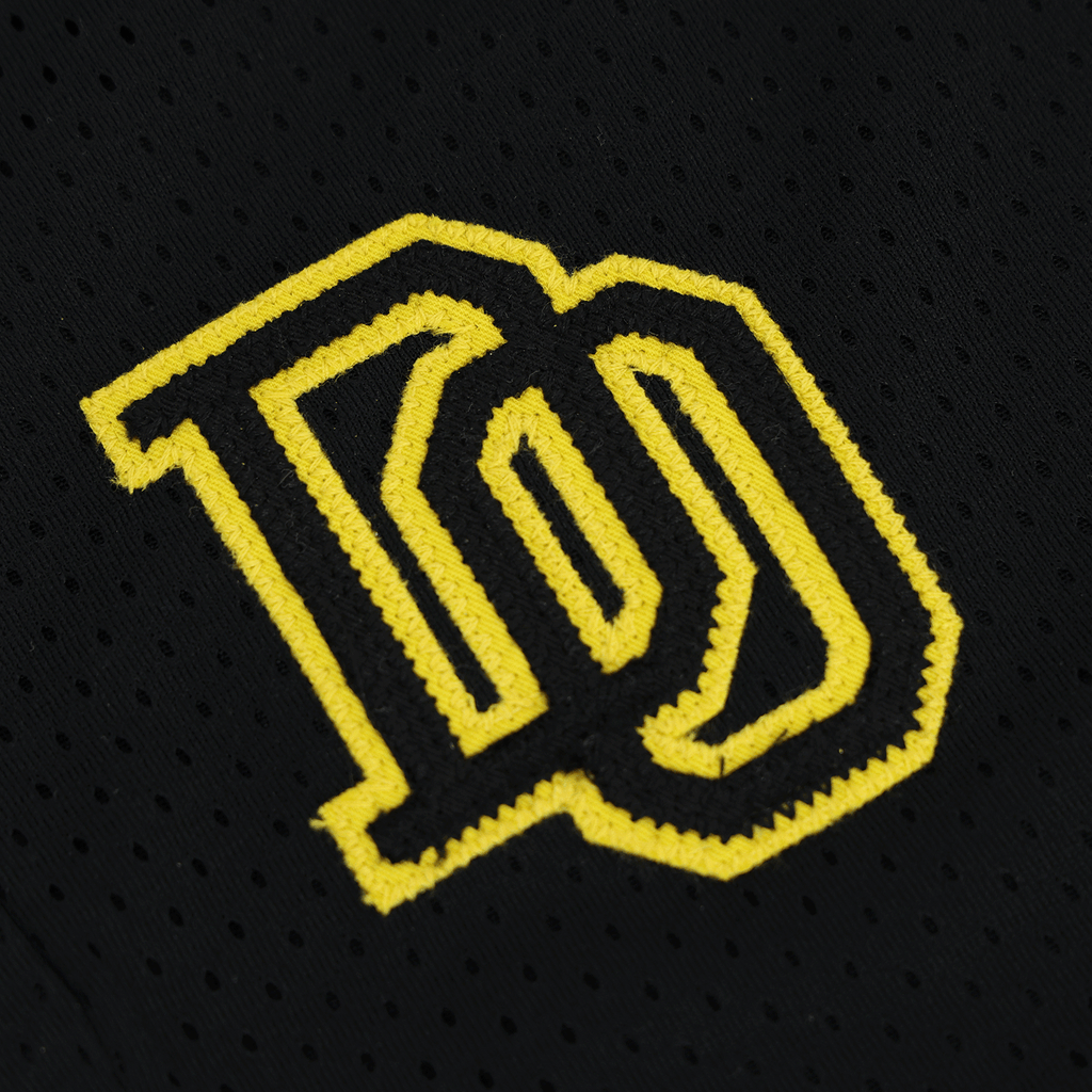 黒い生地に刺繍された黄色のBVBロゴのクローズアップ。BVBカレッジの子供用スウェットショーツの一部。
