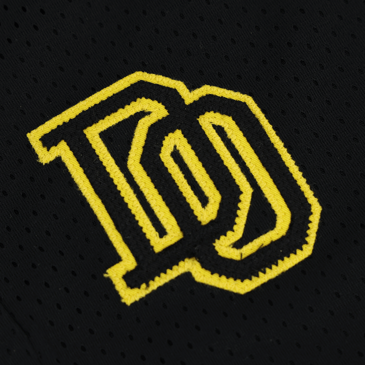 黒い生地に刺繍された黄色のBVBロゴのクローズアップ。BVBカレッジの子供用スウェットショーツの一部。