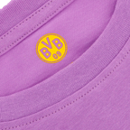 Primer plano de una camiseta infantil del BVB de color lila con el logotipo amarillo del Borussia Dortmund en la nuca.