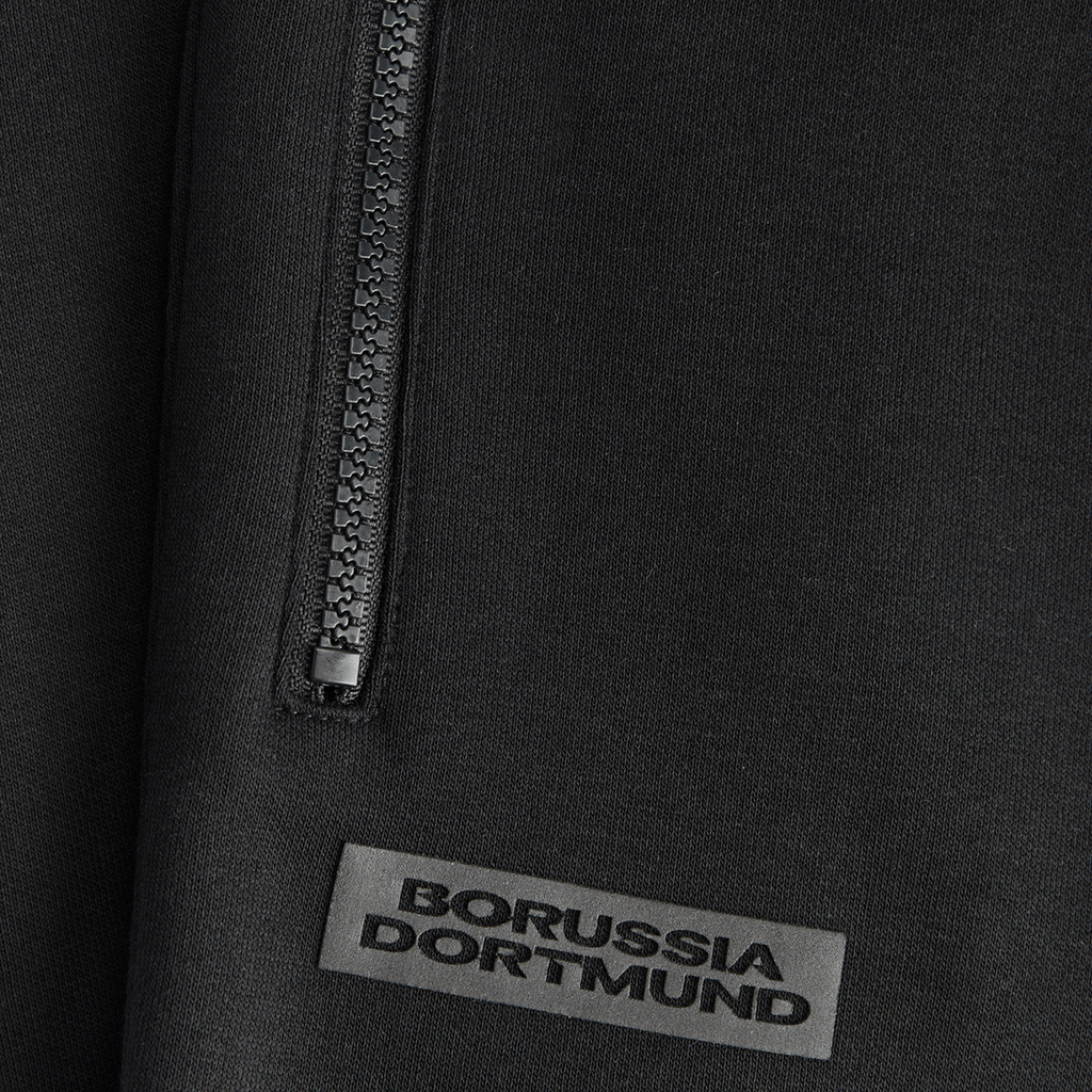 Schwarze BVB Essential Sweatpants für Kinder mit Borussia Dortmund Logo und Reißverschluss-Detail, ideal für Freizeit und Sport.