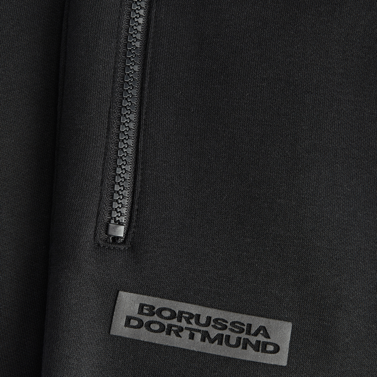 Schwarze BVB Essential Sweatpants für Kinder mit Borussia Dortmund Logo und Reißverschluss-Detail, ideal für Freizeit und Sport.