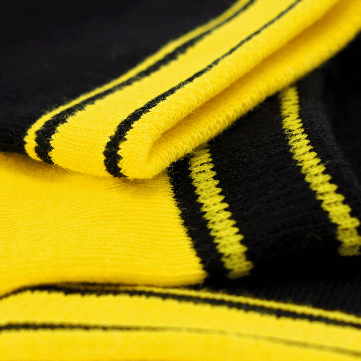 Primo piano di un set di calzini del BVB per bambini con motivo a strisce nere e gialle, ideale per i tifosi del Borussia Dortmund.