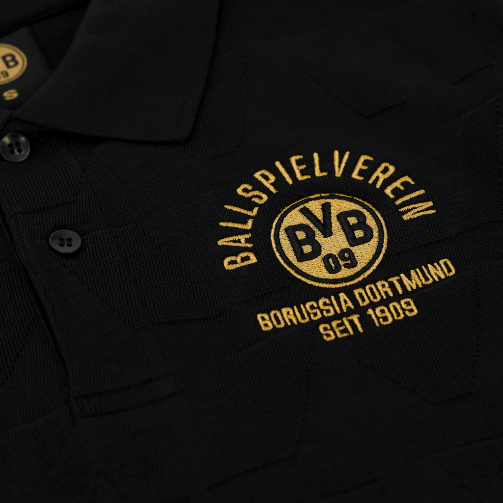 Polo nera del BVB della collezione di articoli per i tifosi, con logo della società e scritta ricamati in giallo, per i tifosi del Borussia Dortmund.