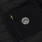 Gros plan sur la veste de stade du BVB 2025, de couleur noire, avec le logo « BVB 09 » blanc et un tirette de fermeture éclair jaune.