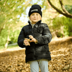 Black BVB reversible jacket for kids with a matching BVB beanie, perfect for fall and winter, modeled by a child in a fall-themed park.