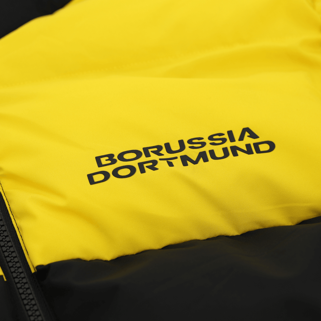 Primo piano della giacca invernale del BVB nei colori nero e giallo con il logo del Borussia Dortmund ben visibile, l'abbigliamento ideale per i tifosi nelle giornate fredde.
