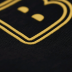 Primo piano del logo su una maglietta nera del BVB con scritta gialla, ideale per i tifosi del Borussia Dortmund.