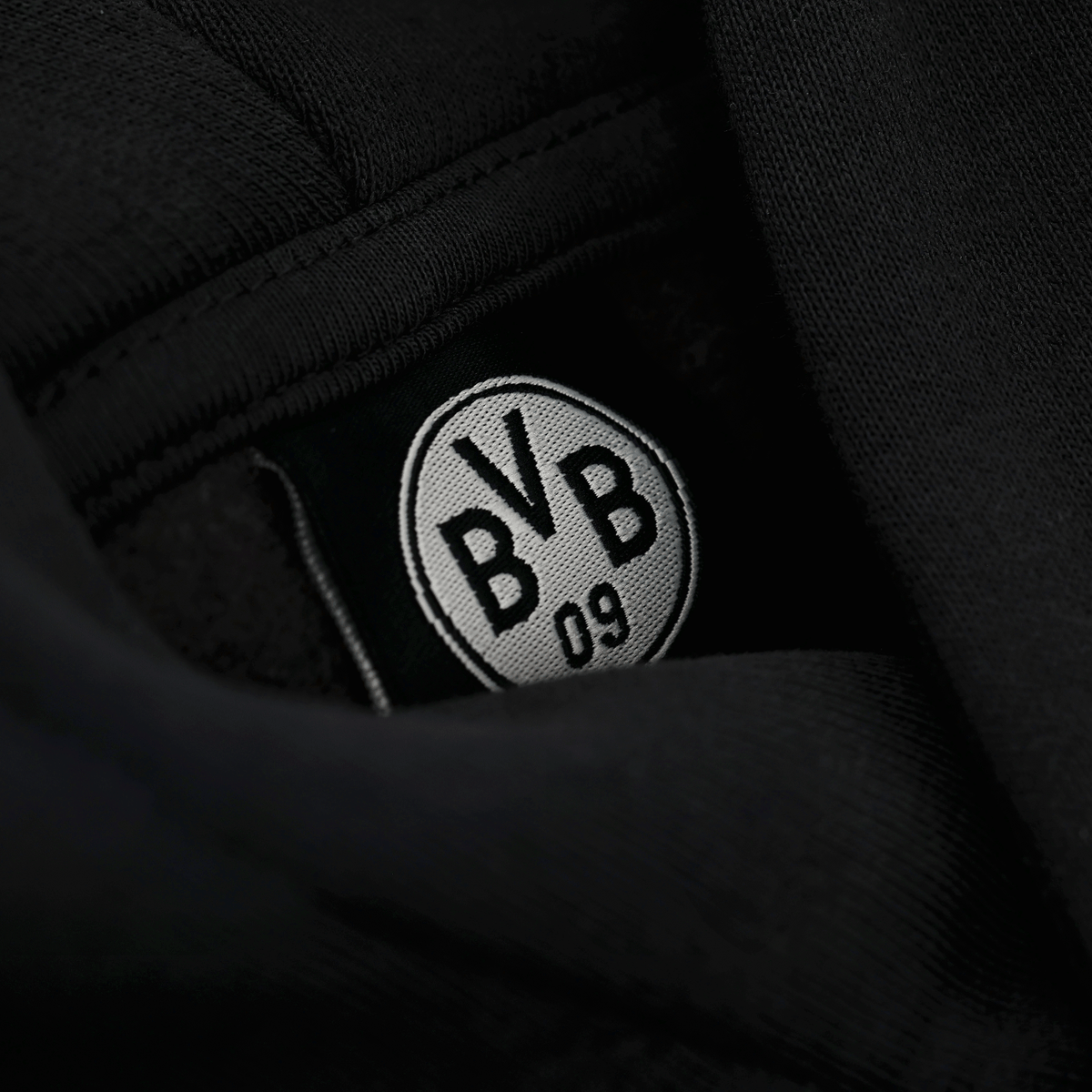Vue détaillée de l'intérieur d'un sweat à capuche noir du BVB, orné d'un logo BVB 09 brodé en noir et blanc.