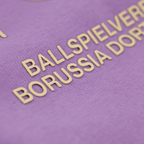 Vista dettagliata di una felpa con cappuccio viola del Borussia Dortmund con la scritta dorata “Ballspielverein Borussia Dortmund”.