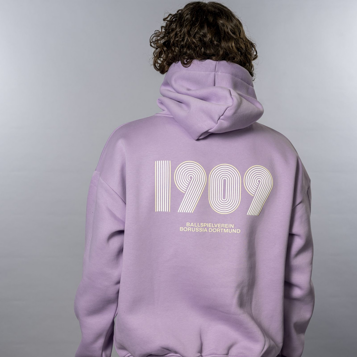 背面に「1909」のグラフィックと「Ballspielverein Borussia Dortmund」のロゴが入った紫色のBVBフーディ。ファンに最適です。