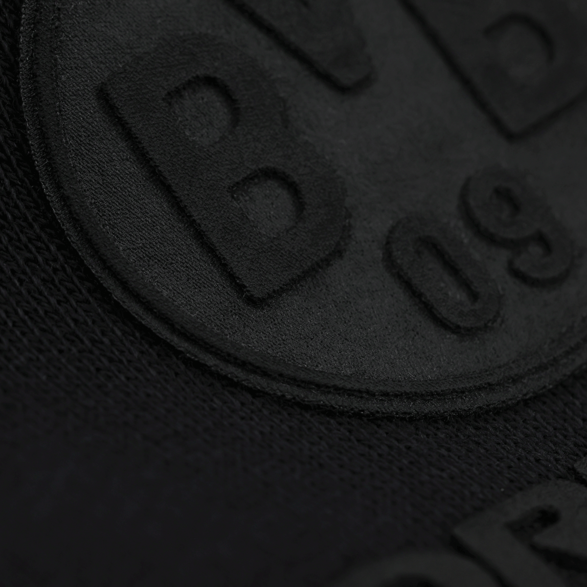 Immagine ravvicinata della felpa con cappuccio nera BVB Core con logo BVB-09 in rilievo, di colore nero su tessuto nero.