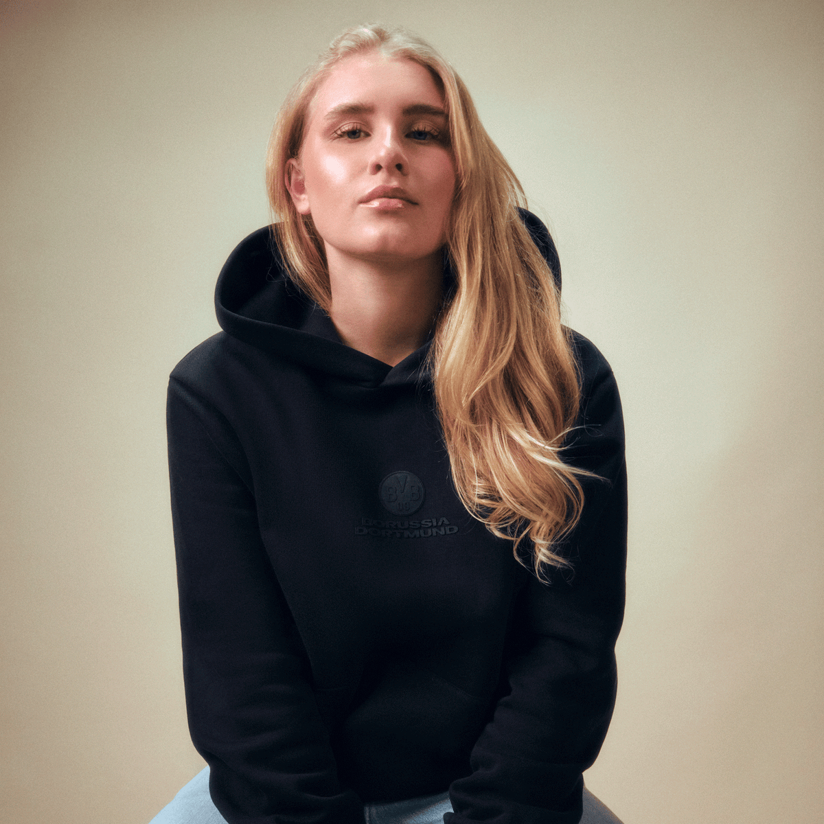Felpa con cappuccio nera della linea BVB Core con un discreto logo del Borussia Dortmund sul davanti, indossata da una donna.