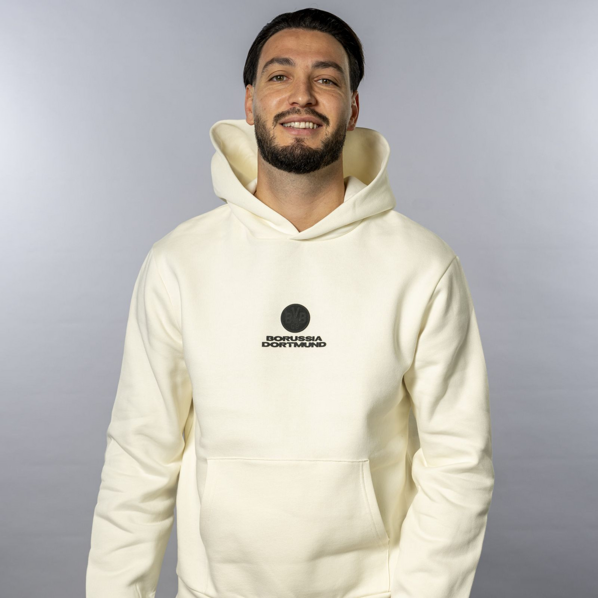 La felpa con cappuccio BVB Core in colore off-white con la scritta “Borussia Dortmund” e un piccolo logo BVB. Perfetta per i tifosi del BVB, comoda ed elegante.