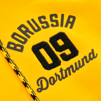 Close-up of the yellow BVB Explorer I sweatshirt jacket featuring an embroidered Borussia Dortmund 09 logo and black-and-yellow decorative patterns.