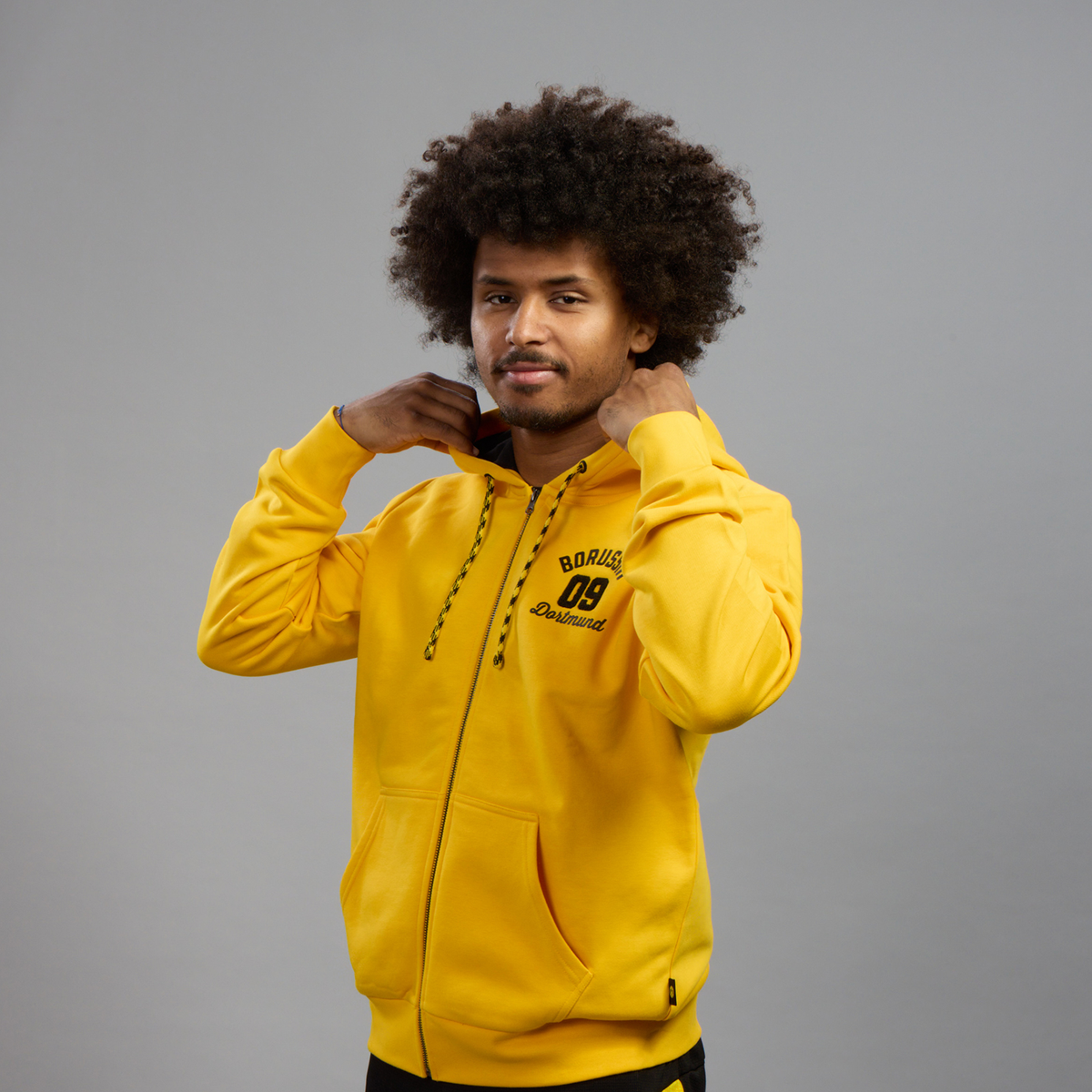 BVB Explorer I Sweatshirt Jacket in yellow with a black BVB 09 Dortmund logo, hood, and zipper—perfect for fans and casual wear.
