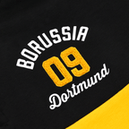 Nahaufnahme eines schwarzgelben BVB-Pullovers mit gesticktem Borussia Dortmund 09 Schriftzug und auffälligem Design auf der Vorderseite.