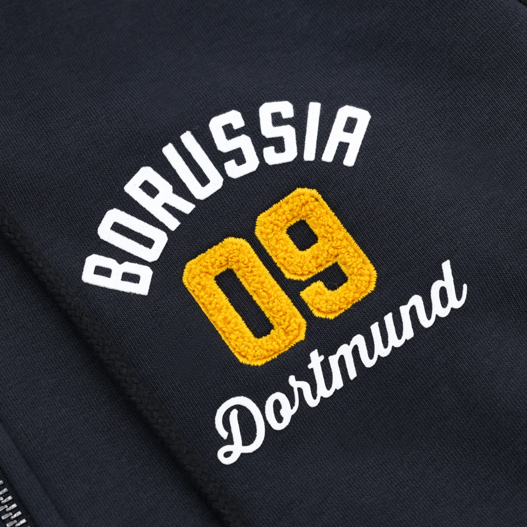 Immagine dettagliata della giacca in felpa BVB Explorer I con il logo del Borussia 09 Dortmund ricamato in giallo e bianco su tessuto nero.