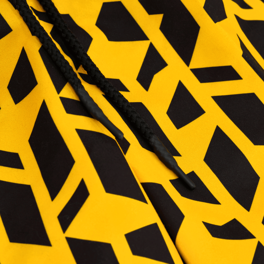 Pantaloncini del BVB Festival II nei colori nero e giallo con motivo geometrico; un primo piano ricco di dettagli mostra i lacci neri.