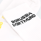 Immagine dettagliata dei calzini bianchi BVB Urban in confezione da 2 con la scritta BORUSSIA DORTMUND in nero e giallo.