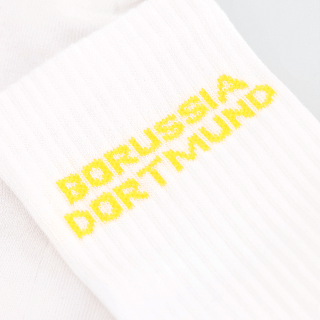 Calzini bianchi del BVB con la scritta “Borussia Dortmund” in giallo in primo piano, perfetti come gadget per i tifosi e come accessorio.