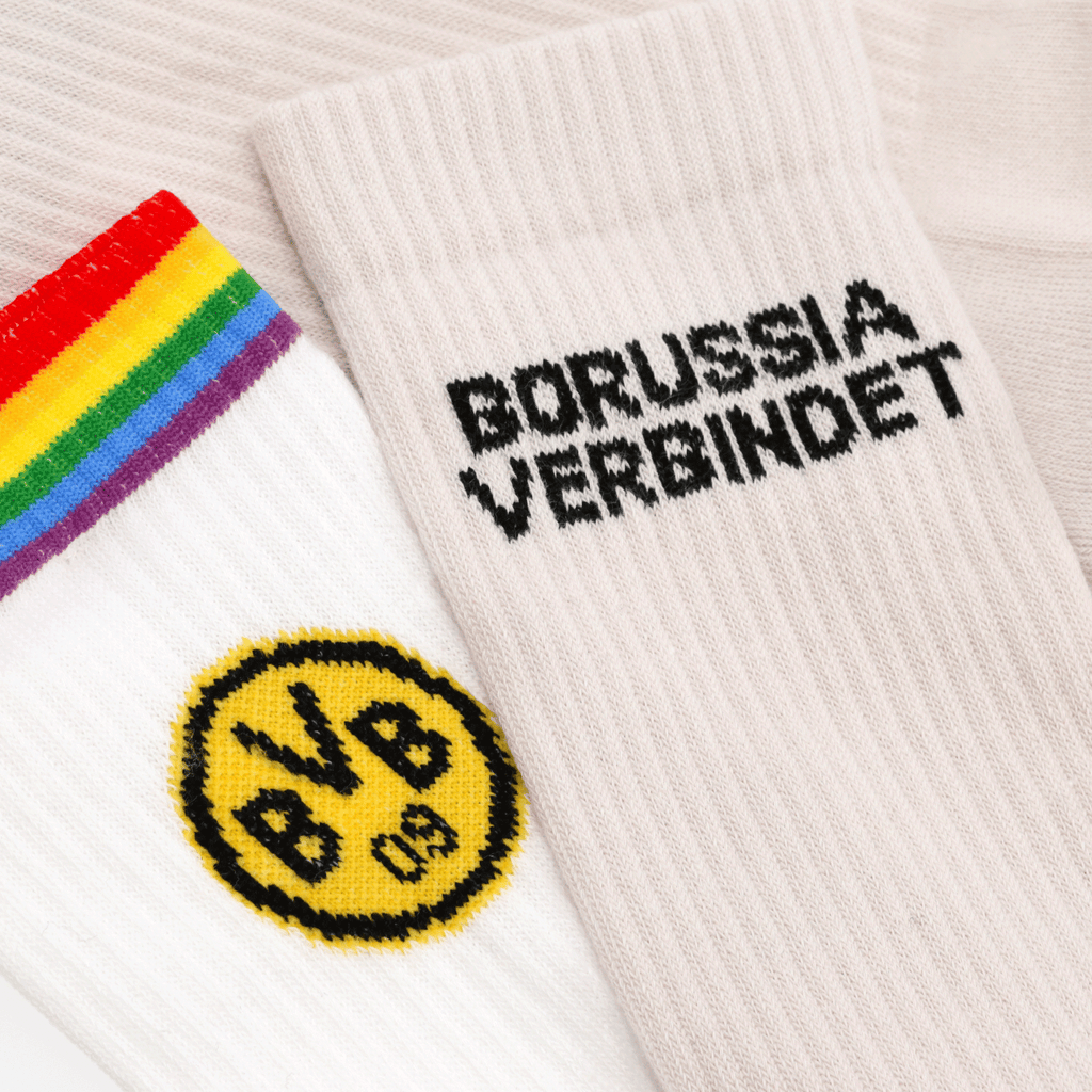 A set of two BVB socks: one with rainbow stripes and a yellow BVB logo, and the other in beige with the black lettering “Borussia verbindet.”