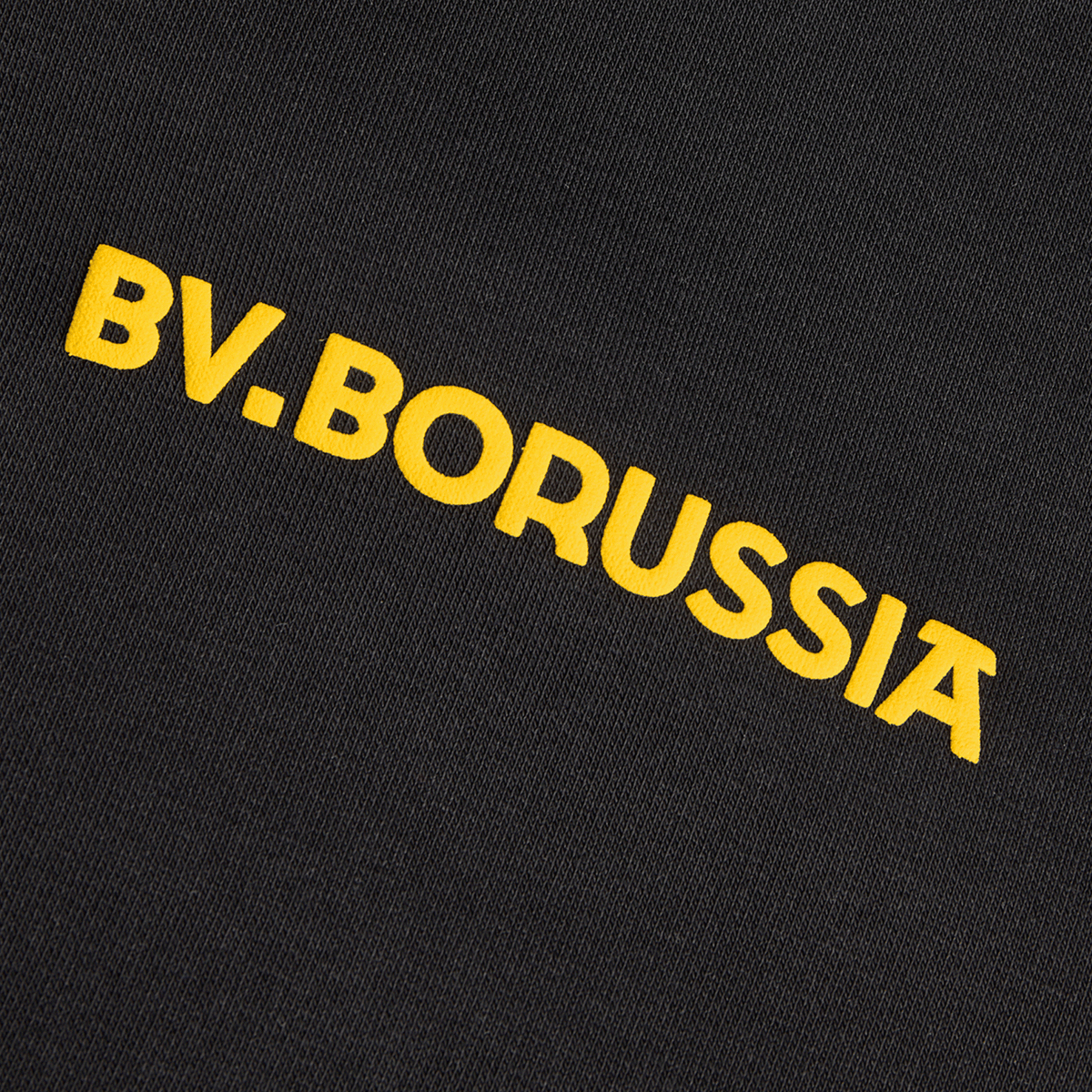 Detailansicht eines schwarzen BVB-Hoodies aus der Kollektion Rote Erde mit gelbem Schriftzug 'BV. Borussia' auf der Vorderseite.