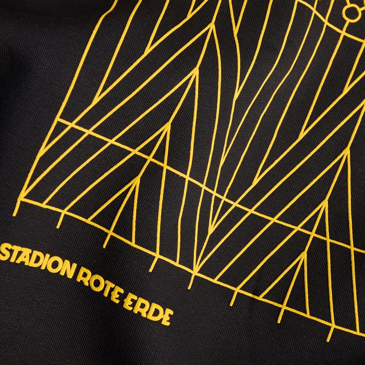 Detailansicht eines schwarzen BVB-Hoodies mit auffälligem gelben Linienmuster und dem Schriftzug 'Stadion Rote Erde', ein stylischer Fanartikel von Borussia Dortmund.