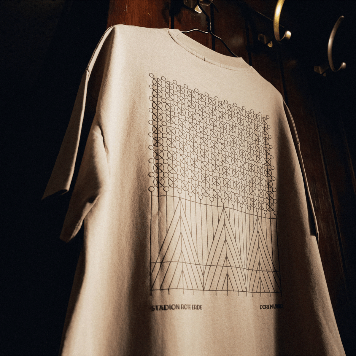BVB T-Shirt Rote Erde in Desert Farbe mit modernem geometrischem Muster und Aufschrift 'Stadion Rote Erde' und 'Dortmund'.