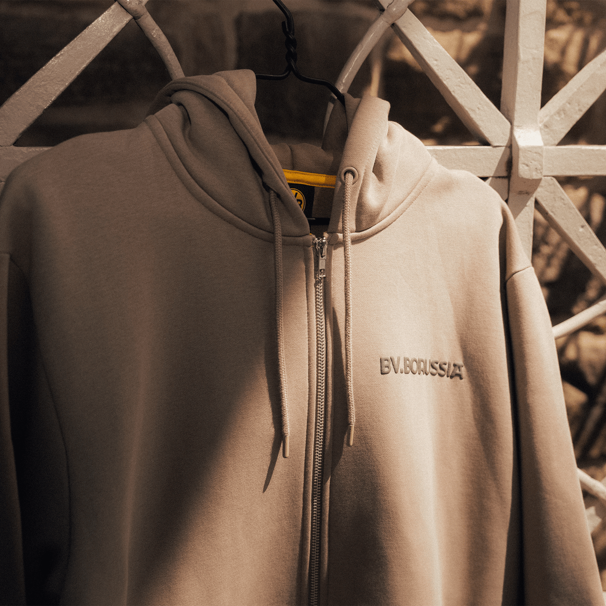 Chaqueta de chándal en color beige con capucha, cremallera y un discreto logotipo de BV.BORUSSIA; diseño moderno, ideal para los aficionados del BVB y para llevar en el tiempo libre.