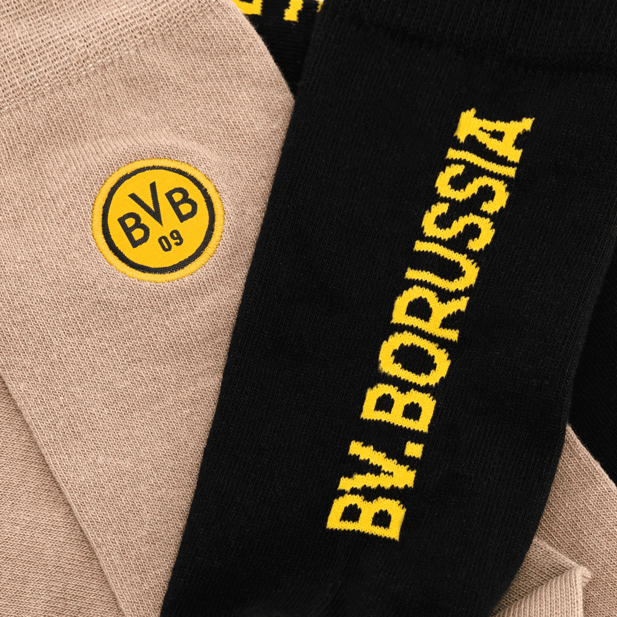 BVB Socken Rote Erde 2er Set bestehend aus schwarzen und beige-farbenen Socken mit BVB 09 Logo und Borussia-Schriftzug, ideal für Fans von Borussia Dortmund.
