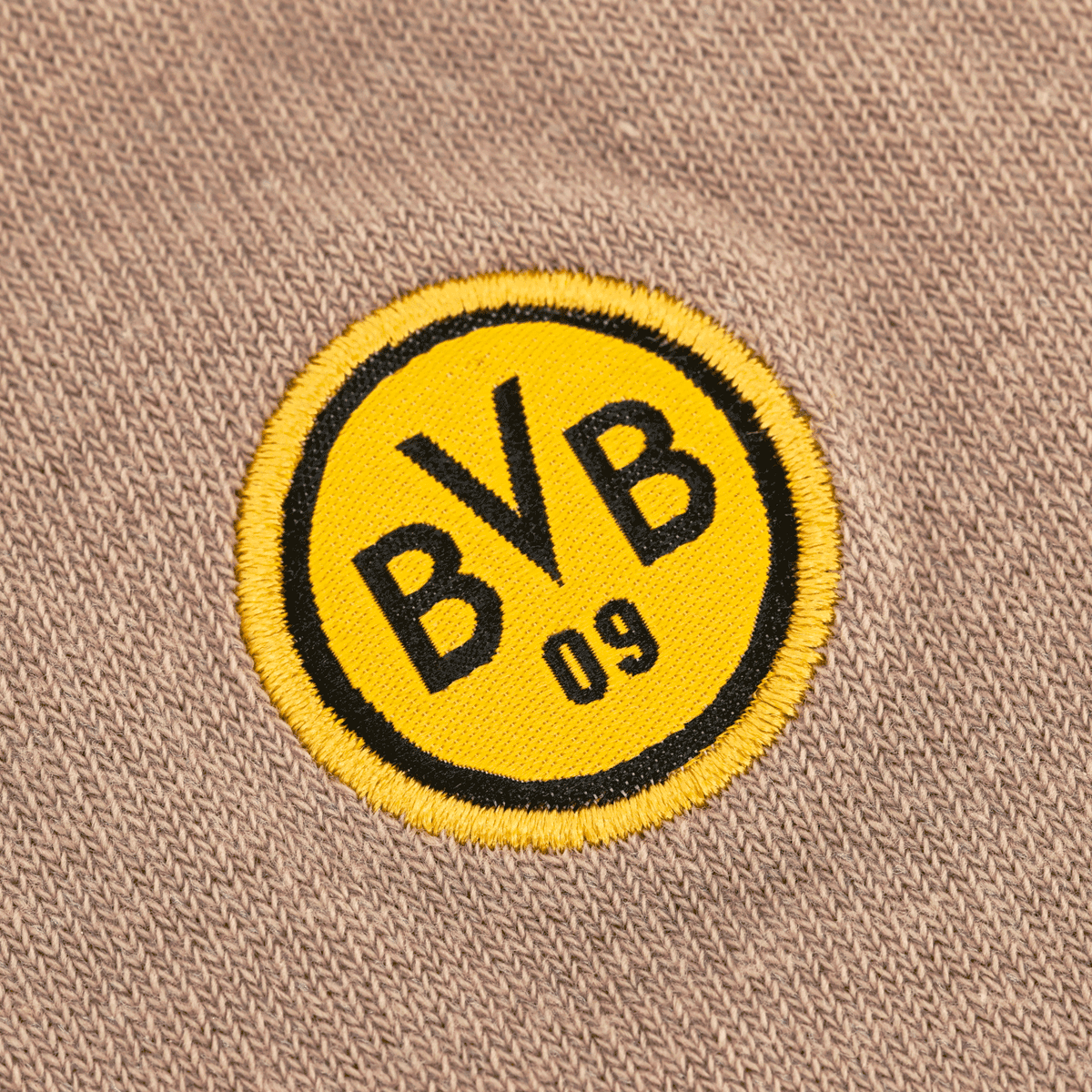 Primo piano del logo del BVB sui calzini "Rote Erde": un emblema circolare giallo con bordo nero e la scritta "BVB 09"