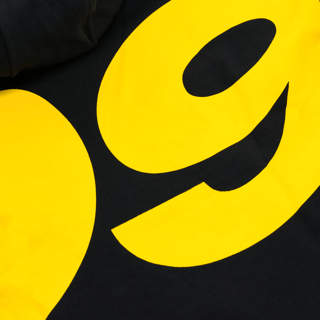 Primo piano di una felpa con cappuccio per bambini del BVB nei colori nero e giallo, con un vistoso logo “09”, ideale per i giovani tifosi del Borussia Dortmund.