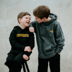 Sweat à capuche BVB Urban Graffiti pour enfants, disponible en noir et gris, avec l'inscription « Borussia Dortmund » en jaune et le motif « Nullneun » : un style moderne et confortable.