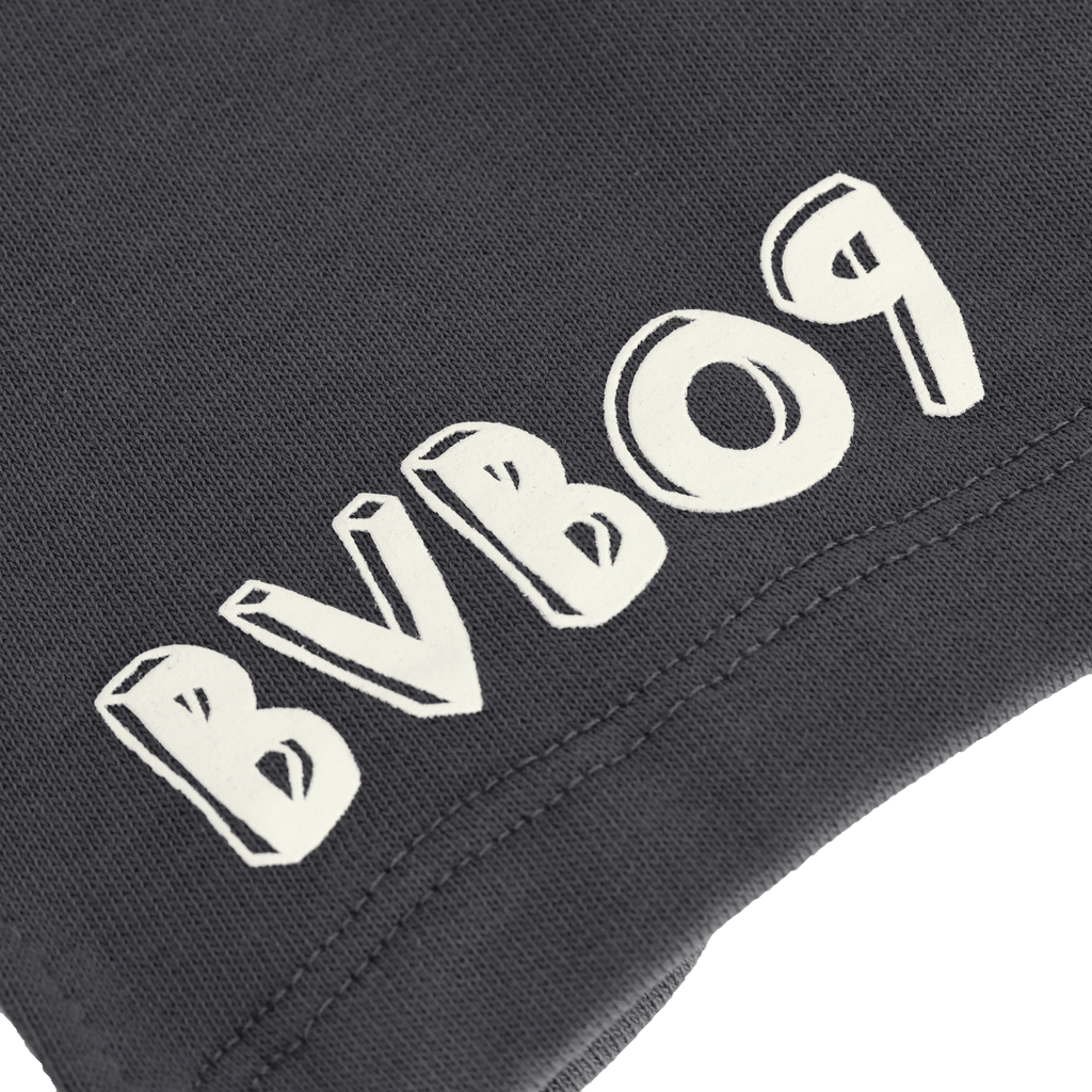 Primer plano de unos pantalones cortos de chándal negros del BVB para niños con un llamativo logotipo blanco del BVB, una prenda ideal para el deporte y el tiempo libre para los jóvenes aficionados.